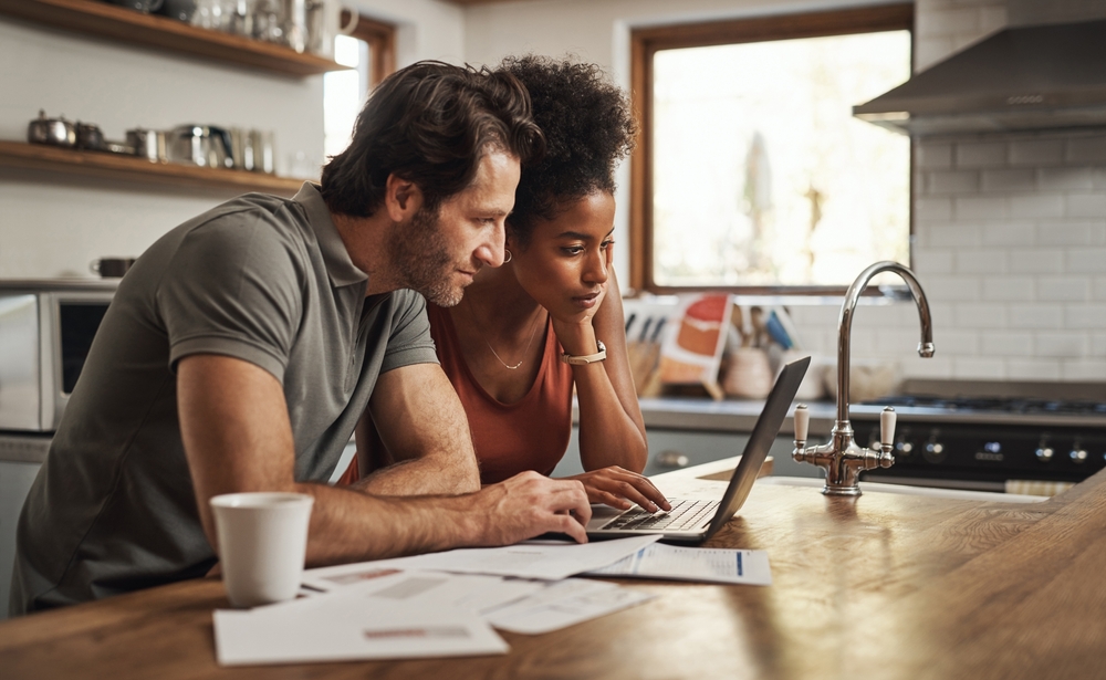 Couple looks at their credit scores on a laptop computer during a research for homeowners insurance options.