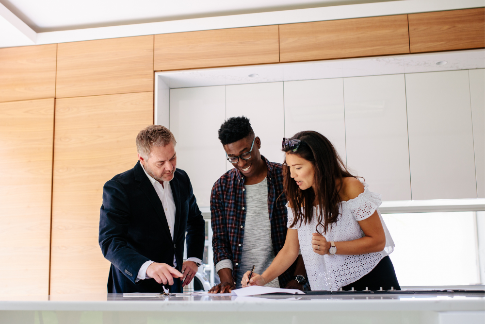 Interracial couple signs on a new homeowners insurance policy with their Matic agent present.