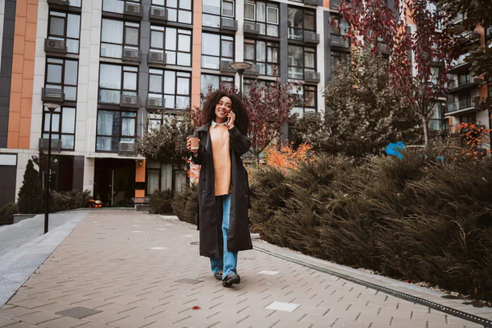 Young black woman talks on her cellphone while walking around her urban residential neighborhood.