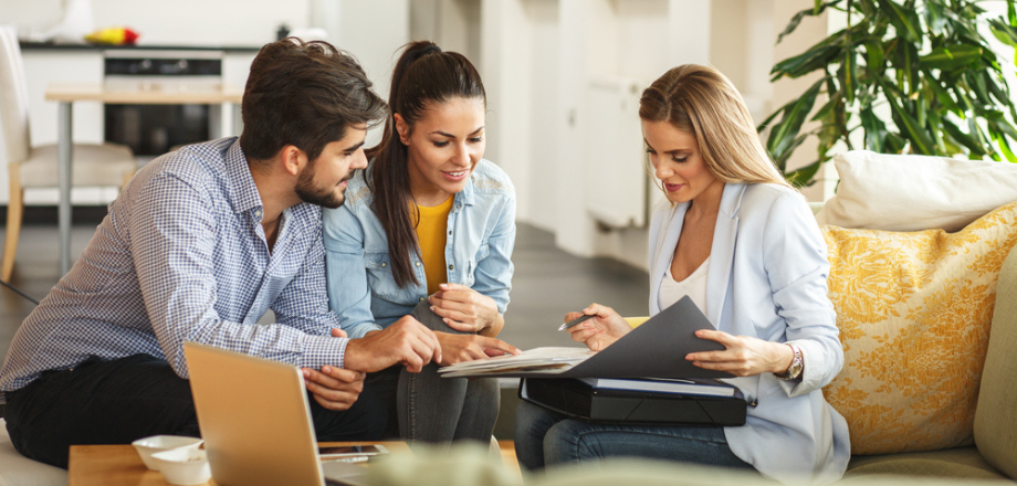 Young couple meets with home insurance agent to discuss rising costs in their premium.