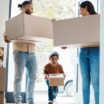 Excited child and parents carrying moving boxes into new home paid through an escrow account.