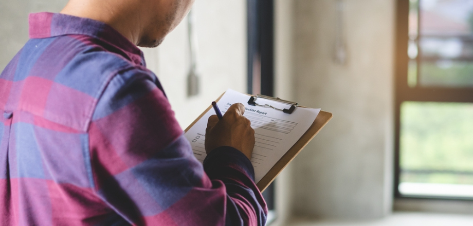 Home inspector takes notes during an interior home inspection for insurance coverage.