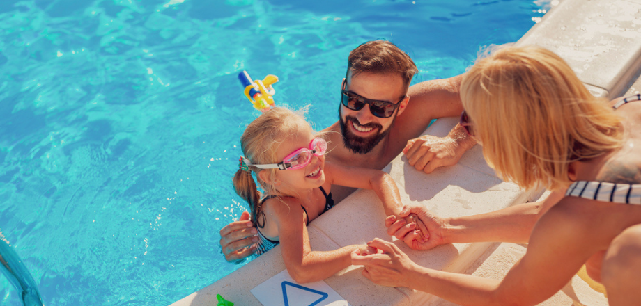 Family swims in pool at their home in the summer.