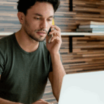 Young male homeowner on the phone with his insurance company asking about filing a homeowners insurance claim.