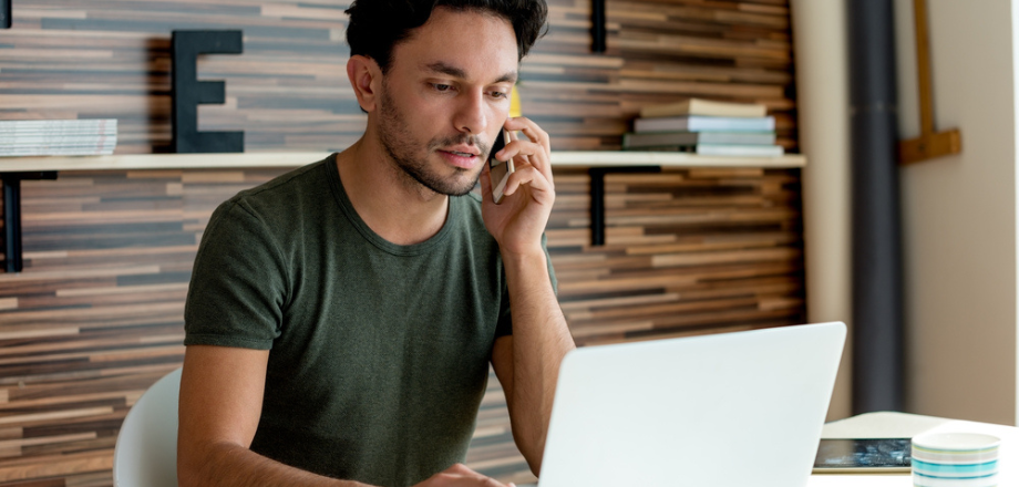 Young male homeowner on the phone with his insurance company asking about filing a homeowners insurance claim.