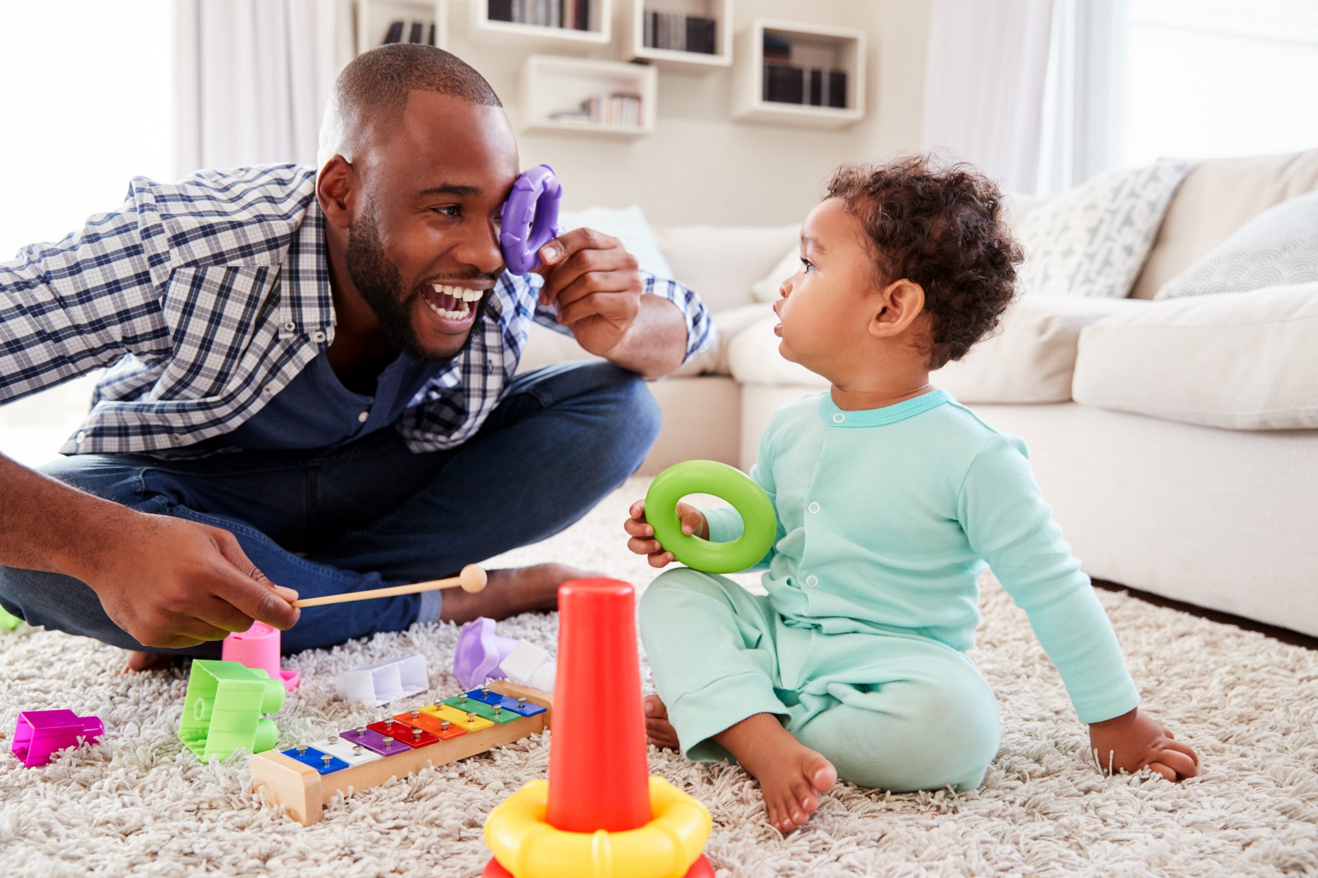 Dad and son playing on the floor with baby toys