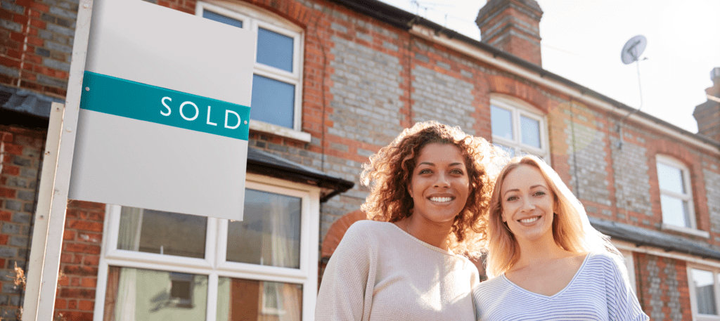 young women outside a house with sold sign