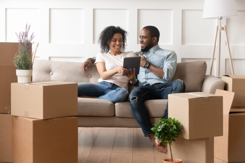 A husband and wife on a couch with moving boxes