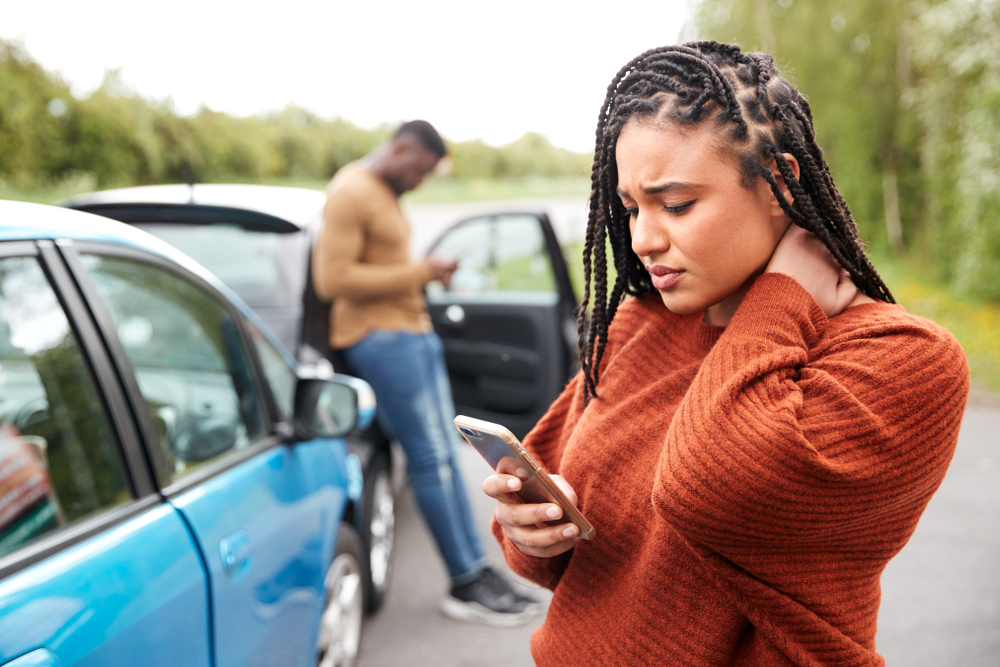 Black female motorist involved in a car accident checks her auto insurance policy with Matic on her phone.