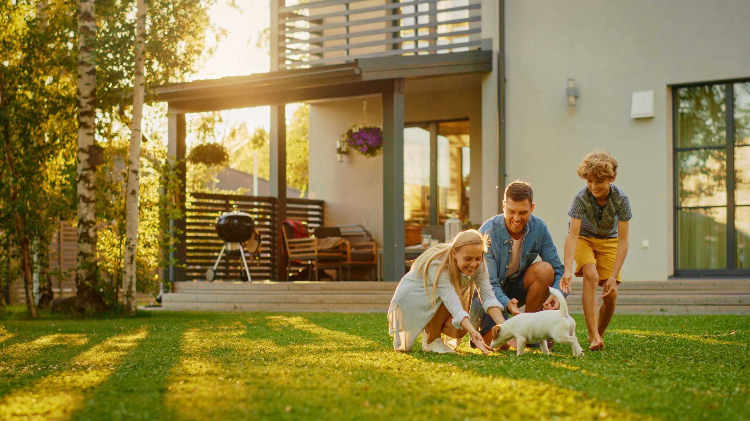 family outside home playing with dog