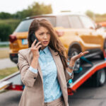 Dark haired woman calls her auto insurance company after she had a car accident.