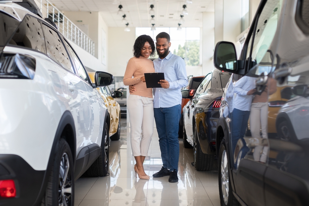 couple signing paperwork at a car dealership