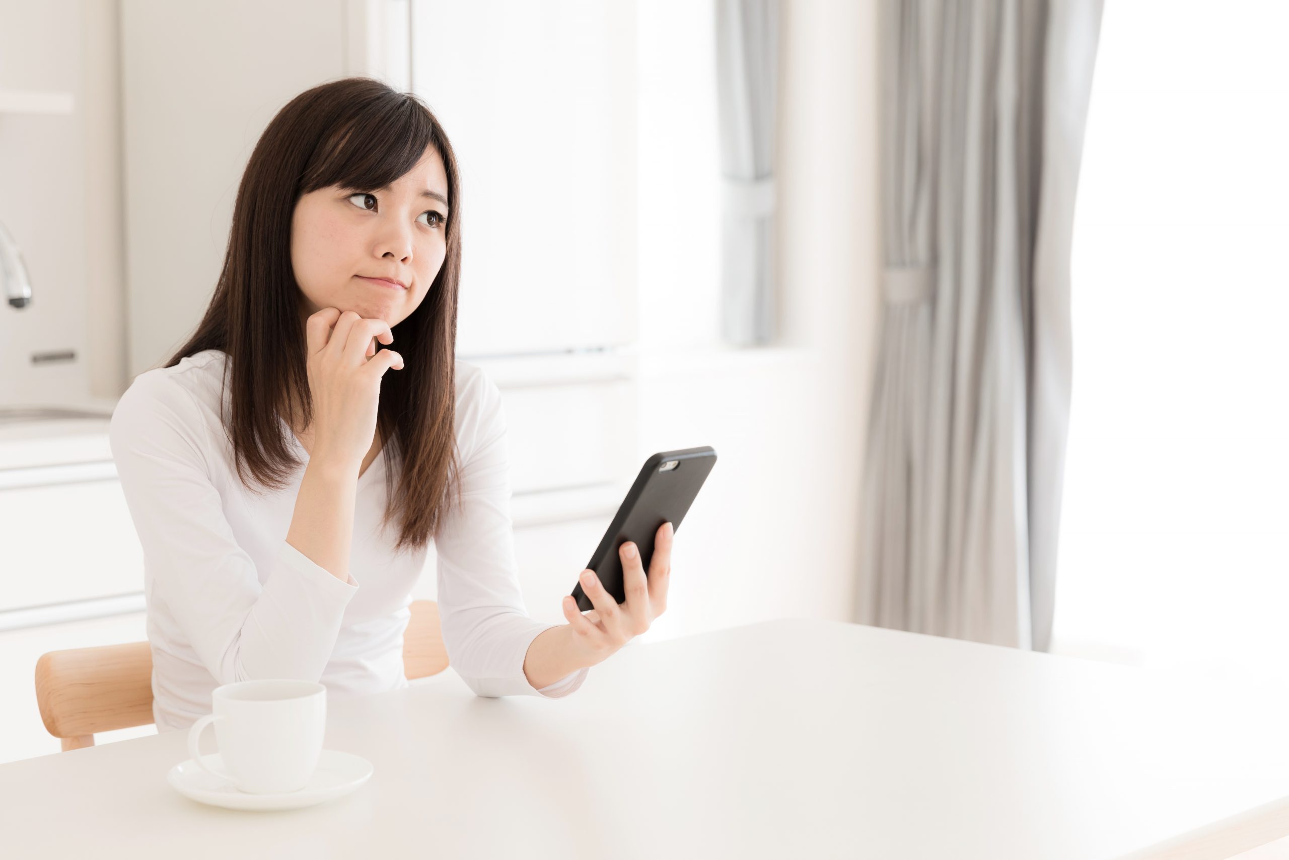 Woman staring at her phone thinking